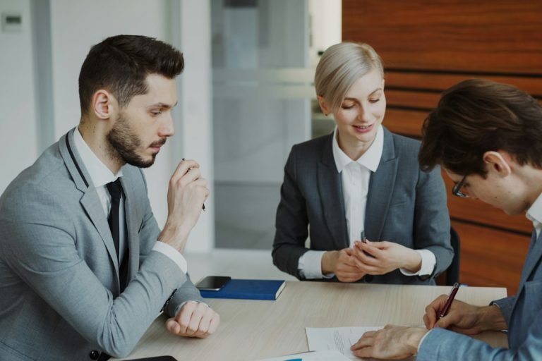 Lawyer and two clients reviewing a document at a meeting table