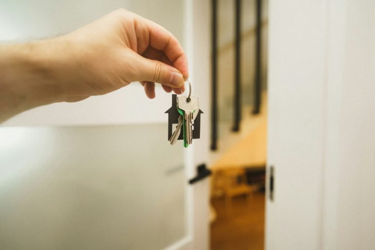 Hand holding house keys beside an open door