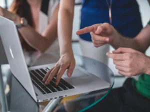 Hands working at a laptop on a shared desk